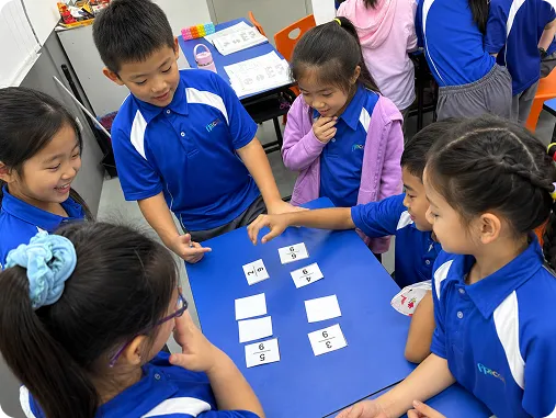 Primary students playing a card game around a table