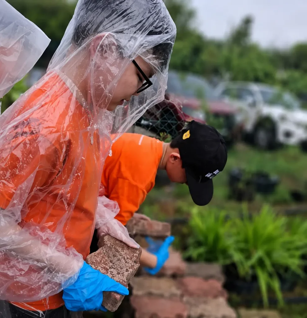 Students in raincoats planting during an environmental awareness activity