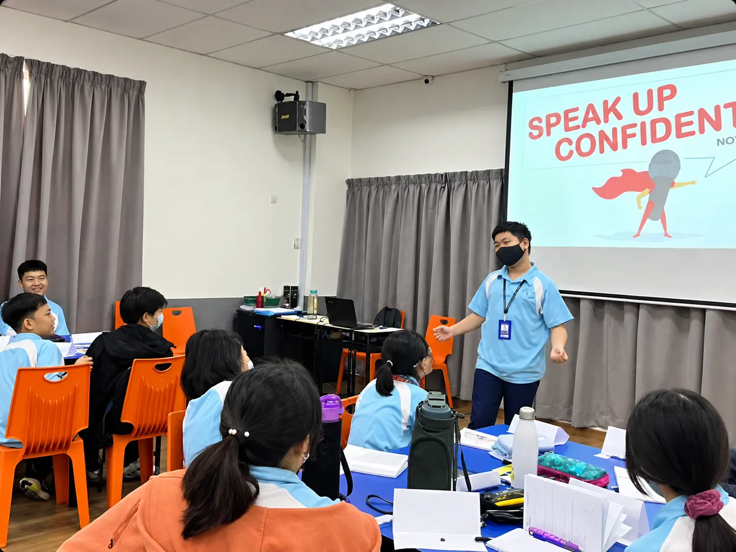 Student presenting in front of a Speak Up Confidently slide